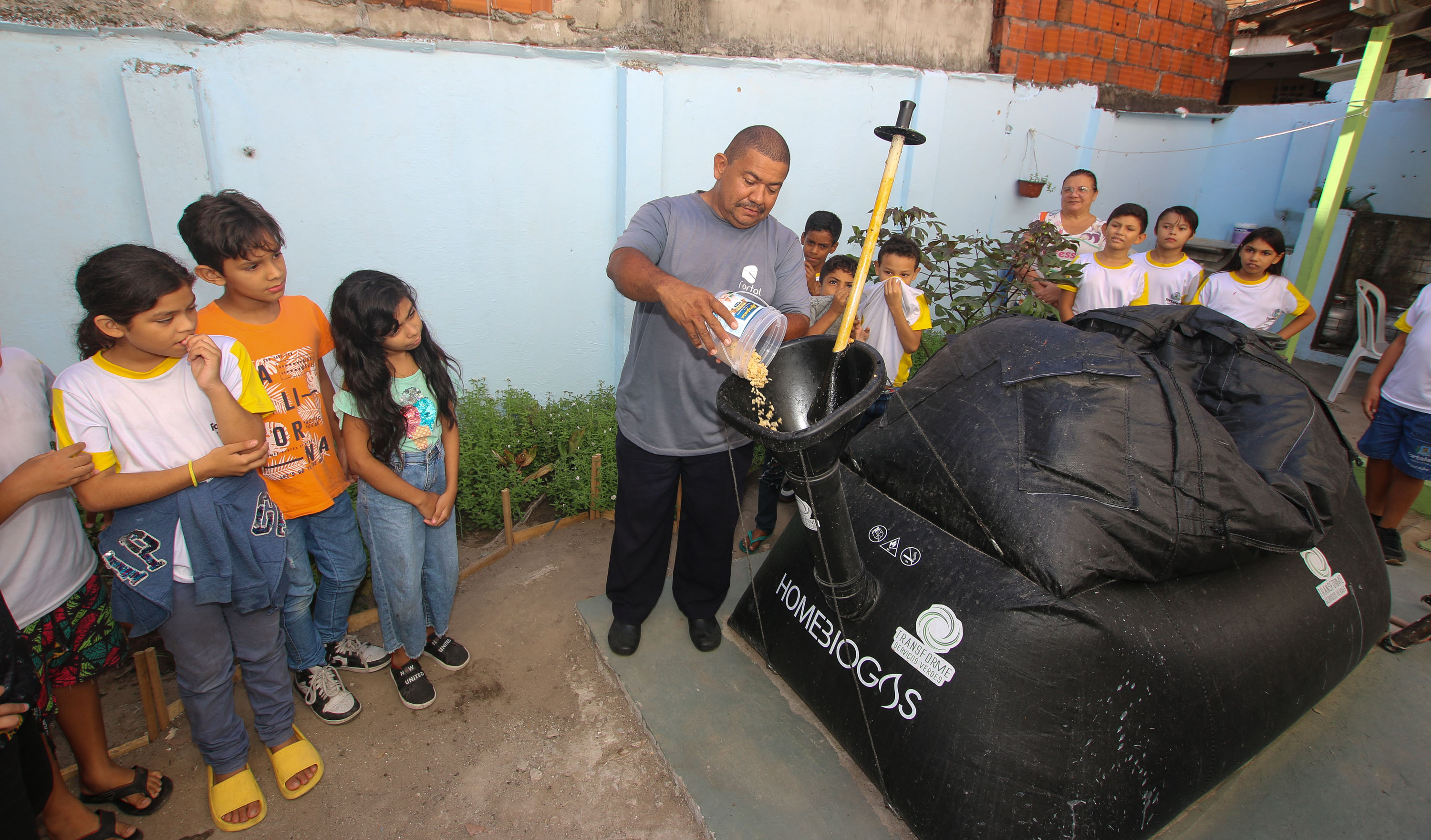 homem coloca restos de alimento de equipamento biodigestor